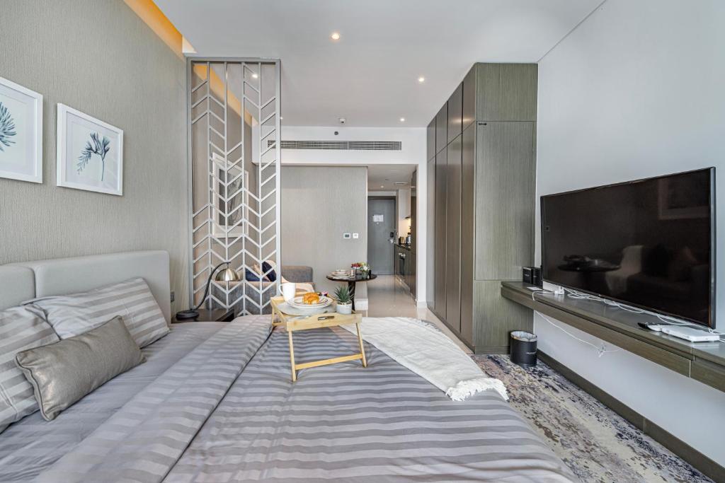 a bedroom with a large bed and a tv at Livin' Holidays - Luxury studio with Bay view in Dubai