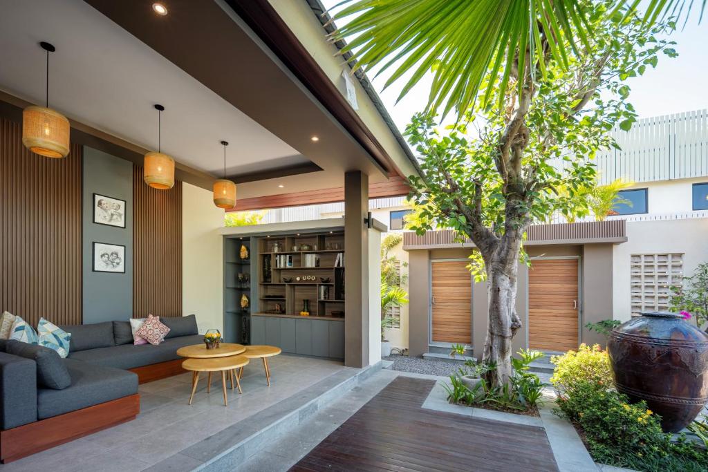 a patio with a couch and a table and a tree at The New Moon Umalas in Seminyak