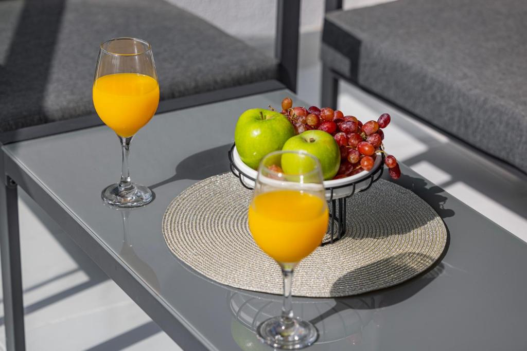 two glasses of orange juice and a bowl of fruit on a glass table at Livin' Holidays - Luxury studio with Bay view in Dubai