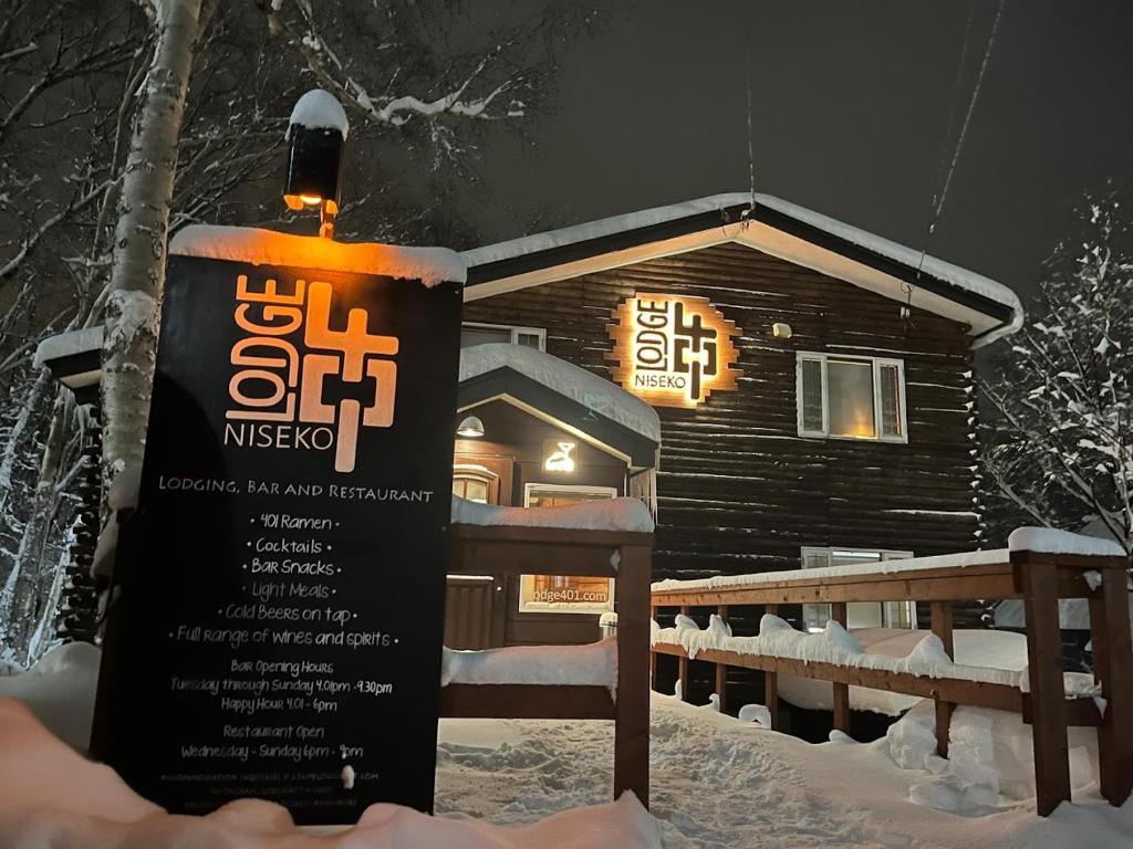 a sign in the snow in front of a log cabin at Lodge 401 Niseko Annupuri in Niseko