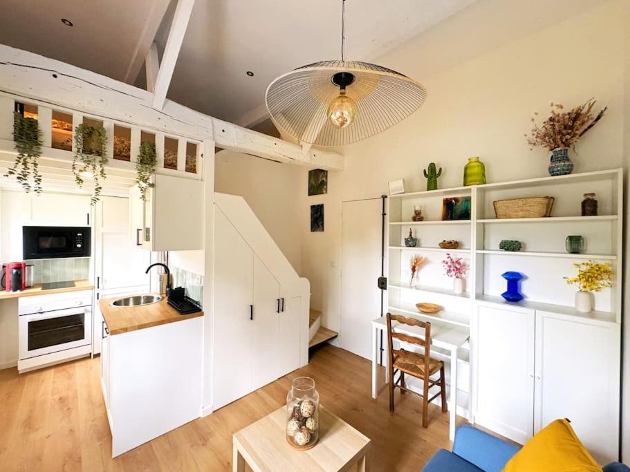 d'une cuisine et d'un salon avec des placards blancs et une table. dans l'établissement Studio cocon aux portes de PARIS, à Saint-Maur-des-Fossés