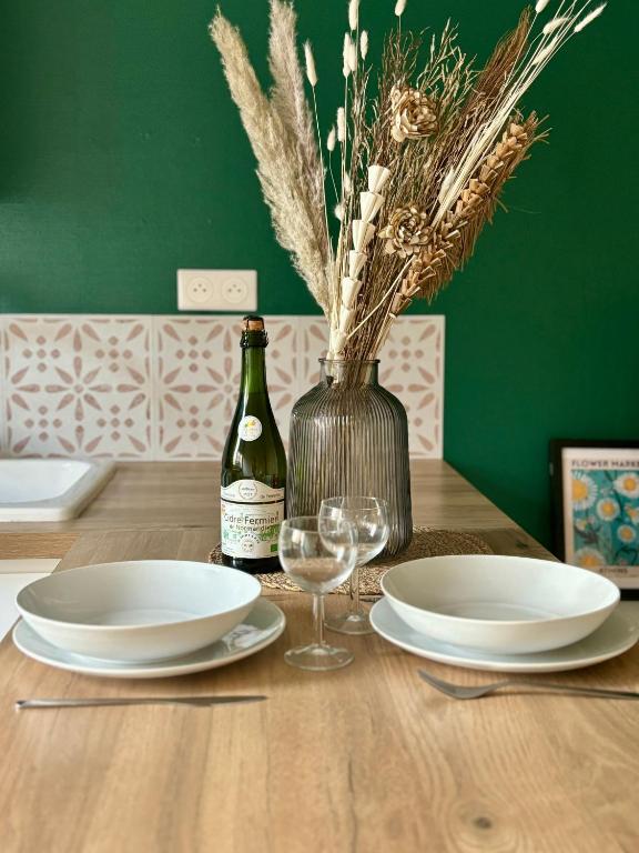 - une table en bois avec 2 assiettes et une bouteille de vin dans l'établissement Appartement proche gare avec garage, à Rouen