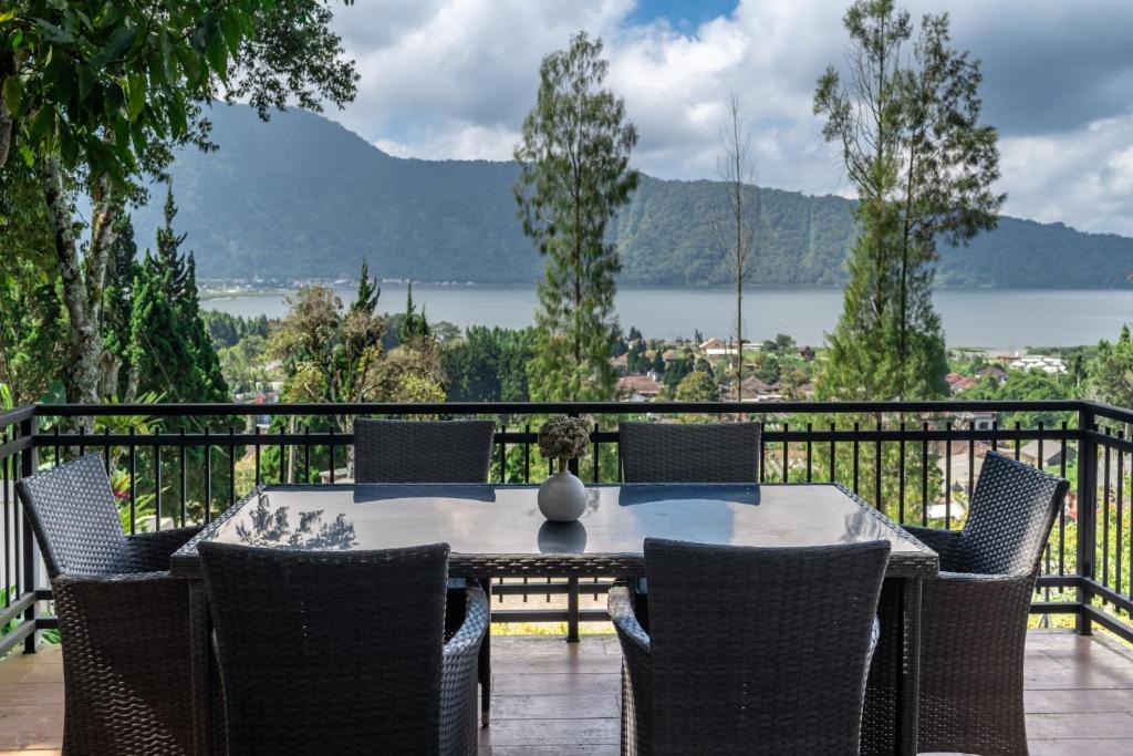 a table and chairs on a balcony with a view of the water at Adara Lake View Residence Bedugul - Bali in Bedugul