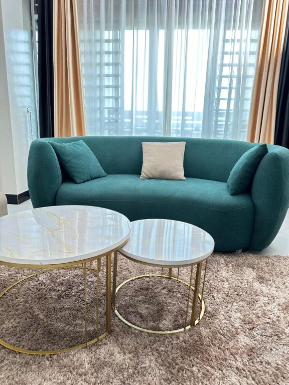 una sala de estar con 2 mesas y un sofá verde en LivLux Apartments 4, en Kampala