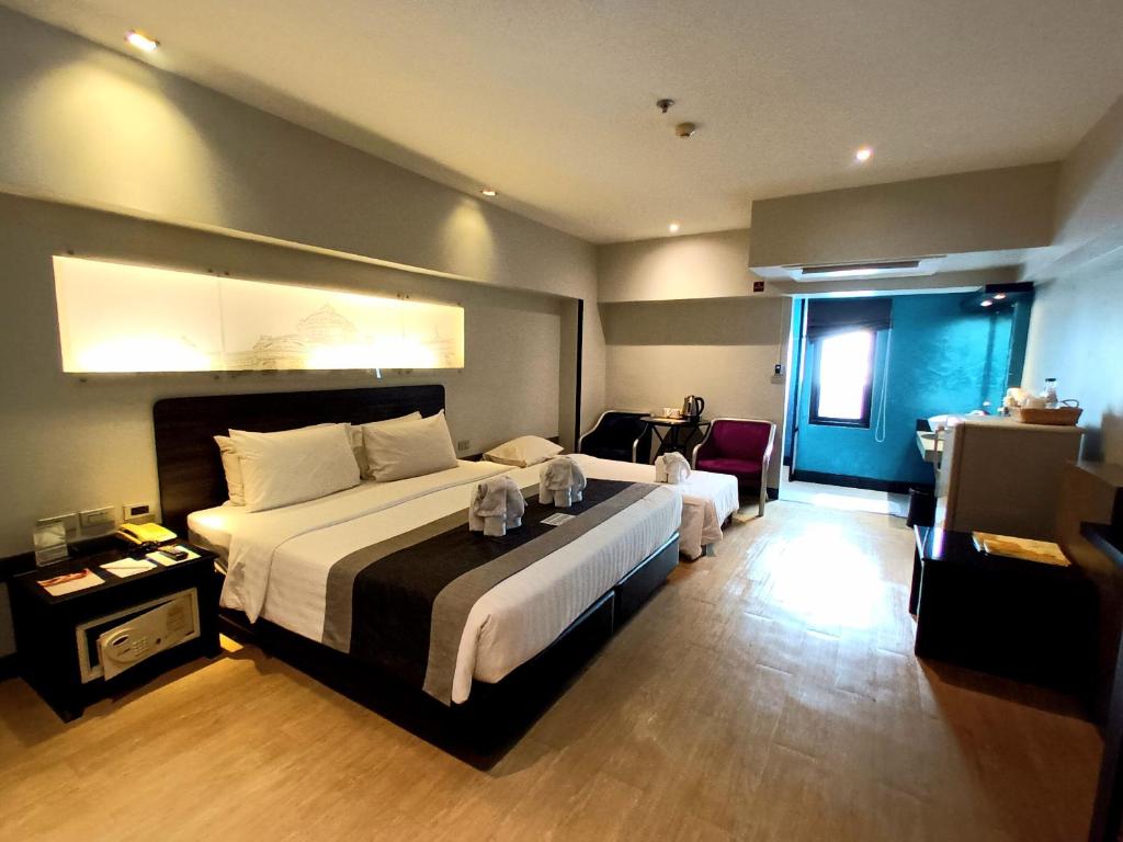 A bright room showing the double bed, single bed, window and storage furniture.