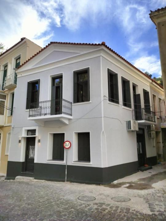 a white building with windows on a street at The Bridge House Plomari in Plomari