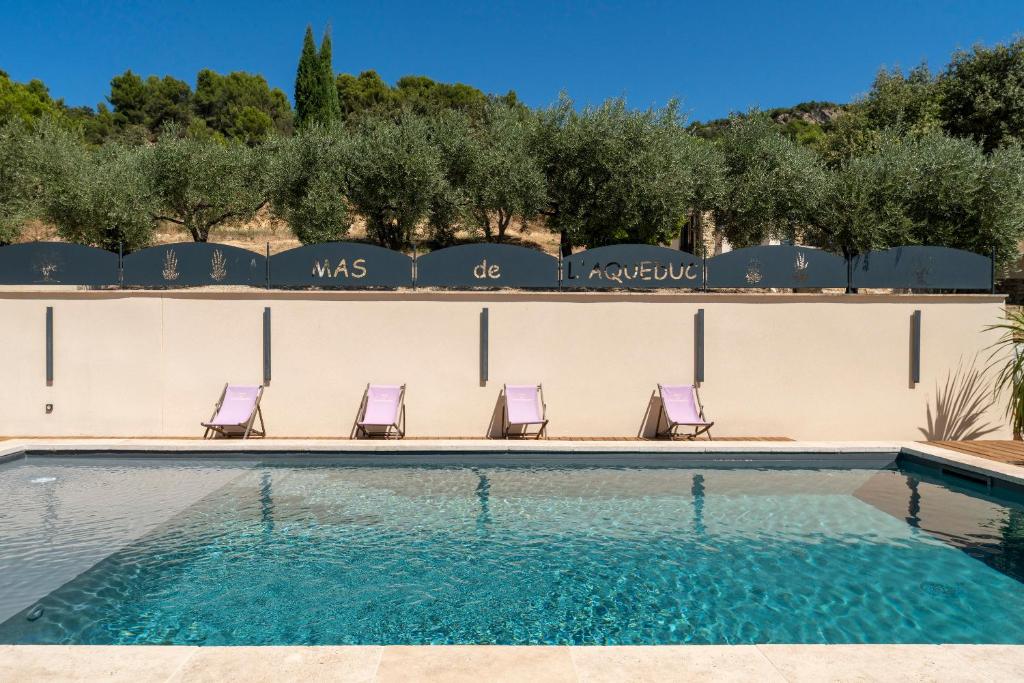 una piscina con sillas moradas junto a una pared en Mas de l'Acqueduc, en Le Barroux