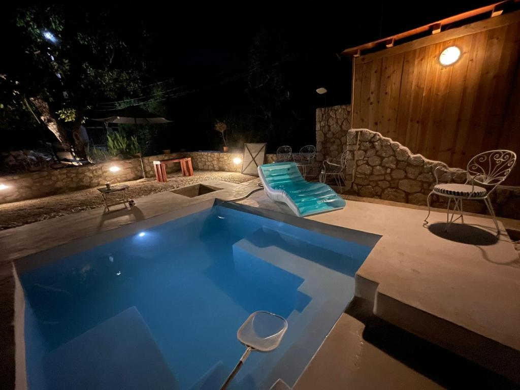 a swimming pool at night with a table and chairs at The 10k Stones Villa in Corfu