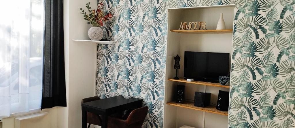 Elle comprend un salon doté d'une télévision et d'un mur avec du papier peint. dans l'établissement L Éclipse, à Aix-les-Bains