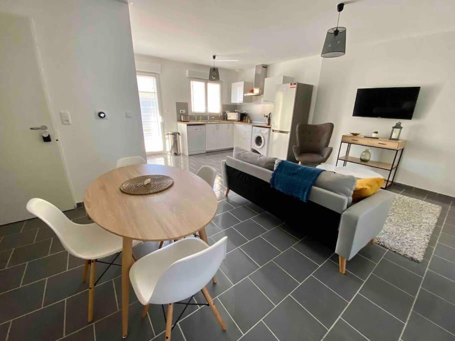 a living room with a couch and a table and chairs at Maison à 300m de la mer avec 2 chambres in Lion-sur-Mer
