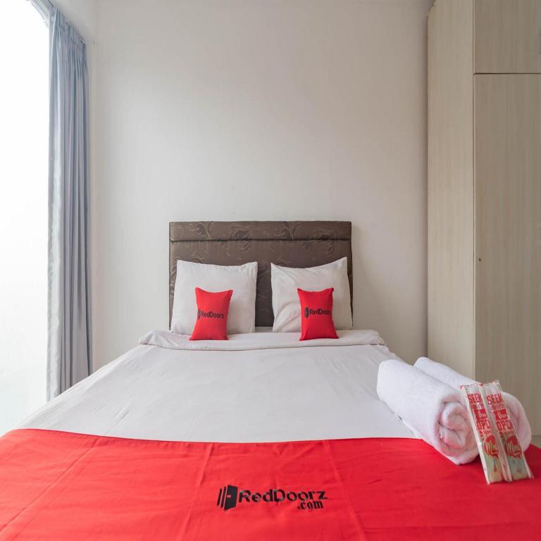 a bedroom with a large bed with red pillows at RedDoorz near Trans Studio Mall Bongo Residence in Bandung