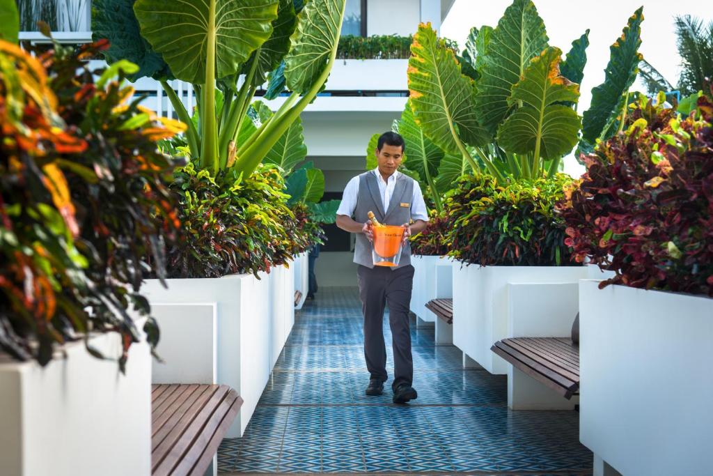 a man walking through a greenhouse with plants at Viroth's Hotel in Siem Reap