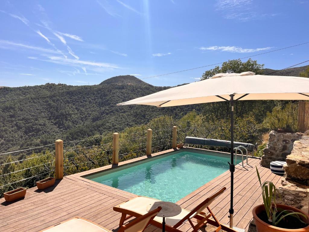 une piscine avec un parasol, une table et des chaises dans l'établissement Maison Ardéchoise au calme avec vue et piscine, à Dunières-sur-Eyrieux