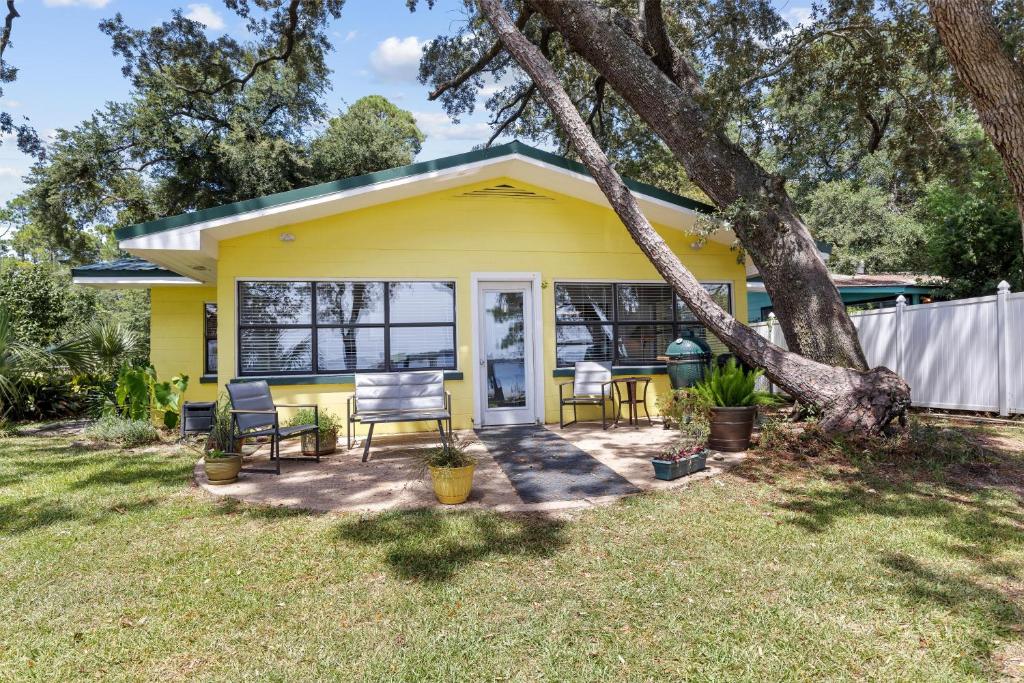 una casa gialla con sedie e un albero di D Cottage Lillian a Lillian