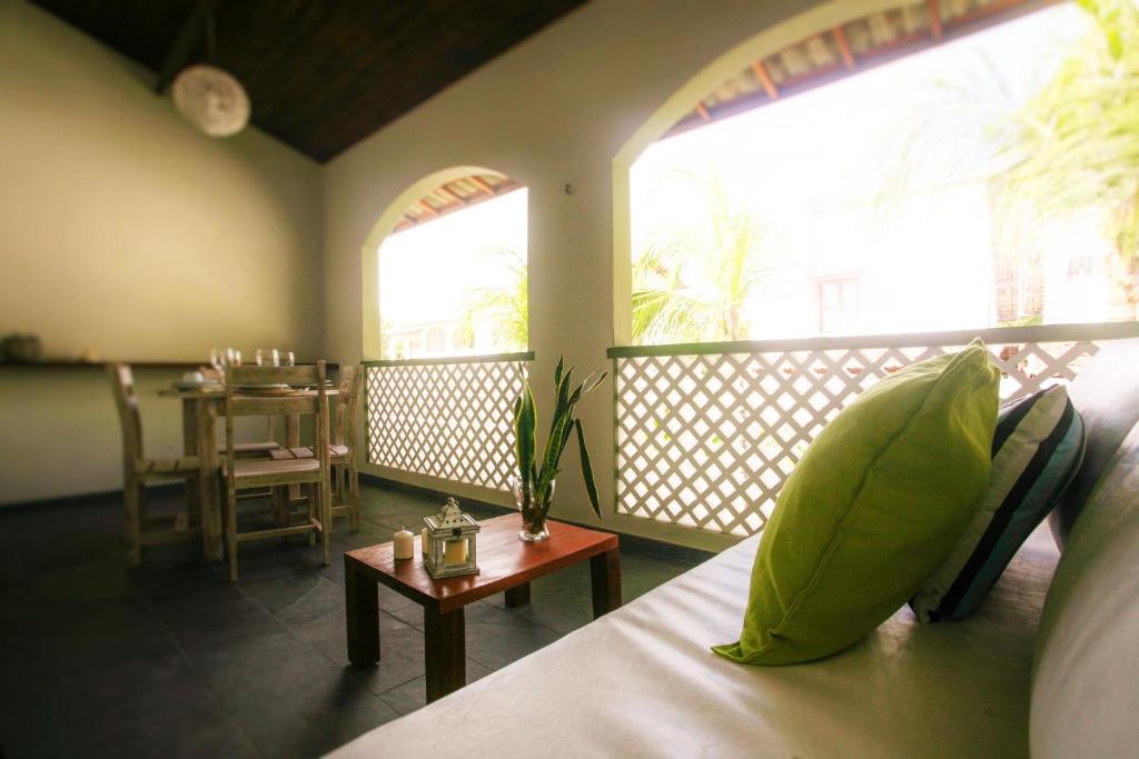 a room with a bed and a balcony with a table at Flor da Mata in Pipa