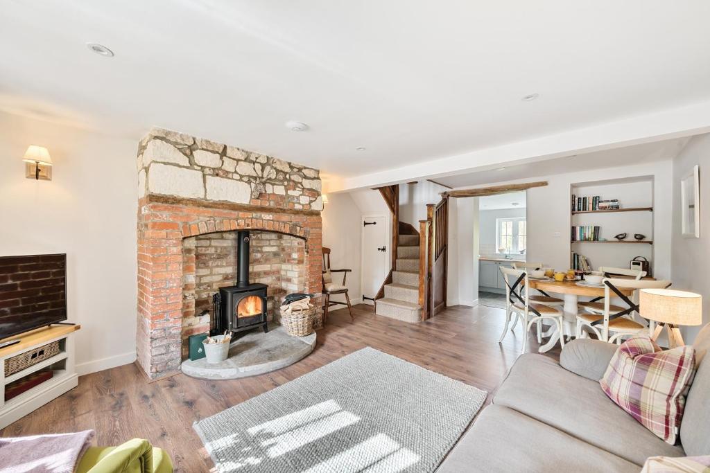 a living room with a brick fireplace and a table at Gamekeeper's Cottage in Dorchester