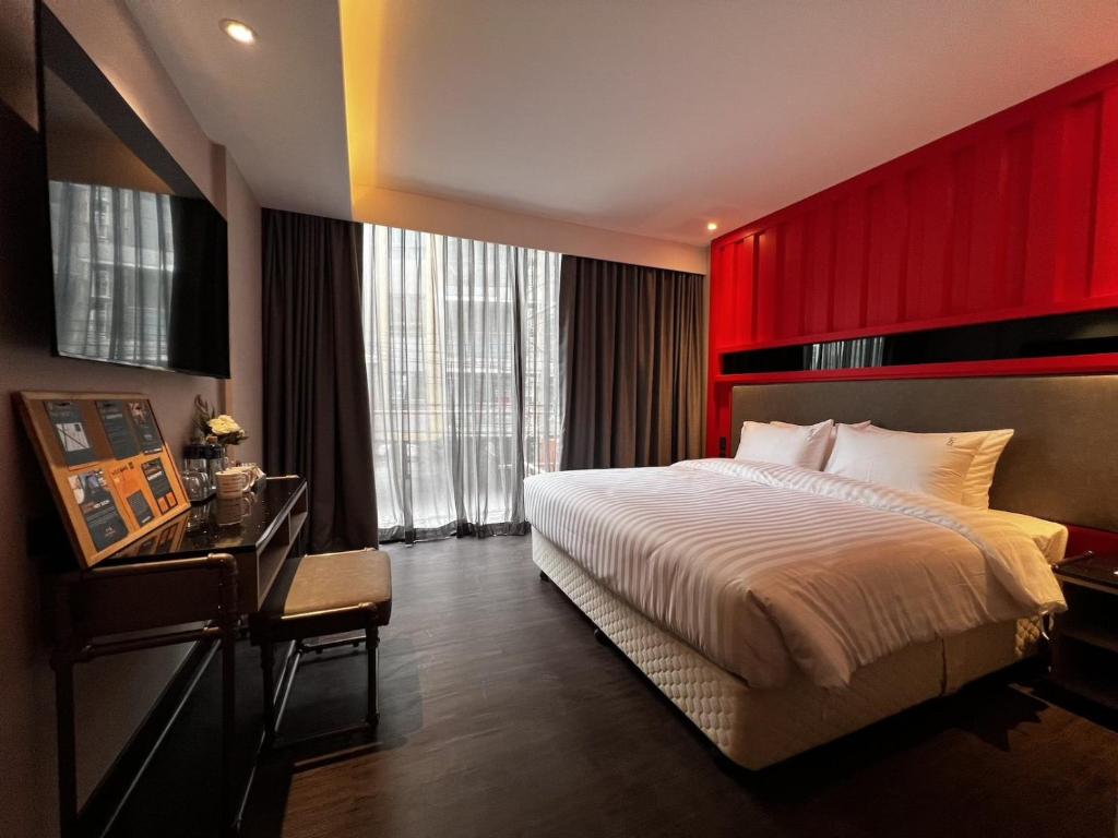 a bedroom with a large bed and a red wall at T2 The Portal Sukhumvit in Bangkok
