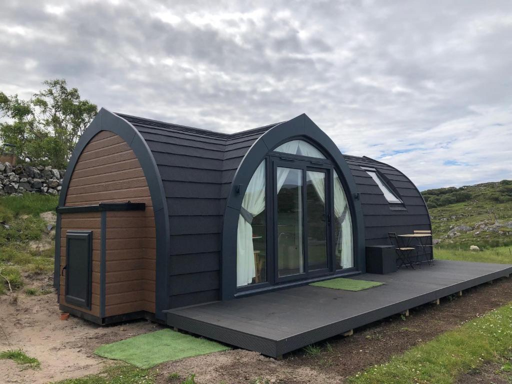 a small black house with a large window at Sandy Meadow Escapes in Lairg
