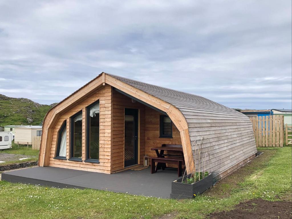 a small wooden cabin with a picnic table in it at Sandy Meadow Escapes in Lairg