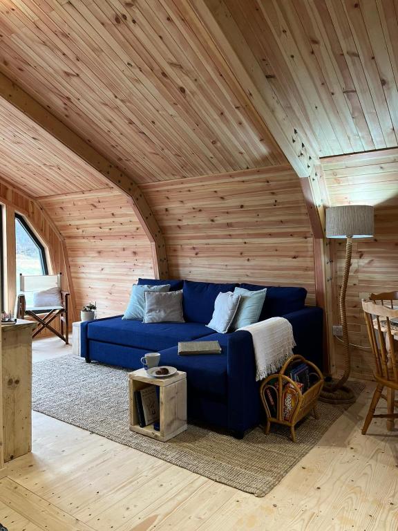a blue couch in a room with a wooden ceiling at Sandy Meadow Escapes in Lairg