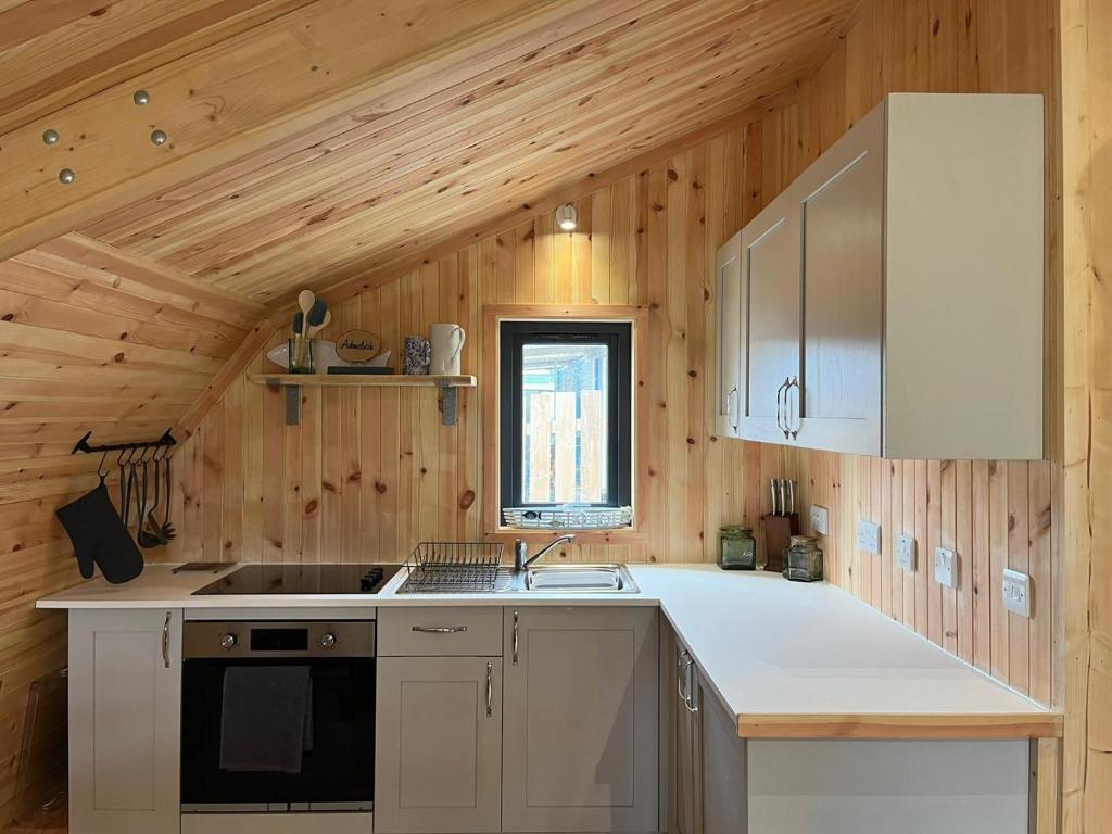 a kitchen with wooden walls and a wooden ceiling at Sandy Meadow Escapes in Lairg