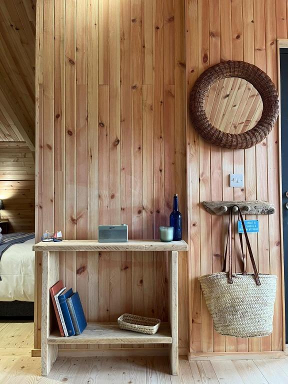 a room with a wooden wall with a shelf and a mirror at Sandy Meadow Escapes in Lairg
