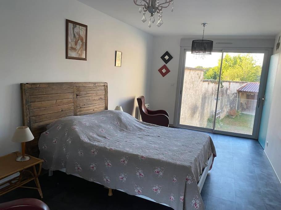 a bedroom with a bed and a large window at Grand T2 indépendant centre ville 1er étage in Saint-Junien