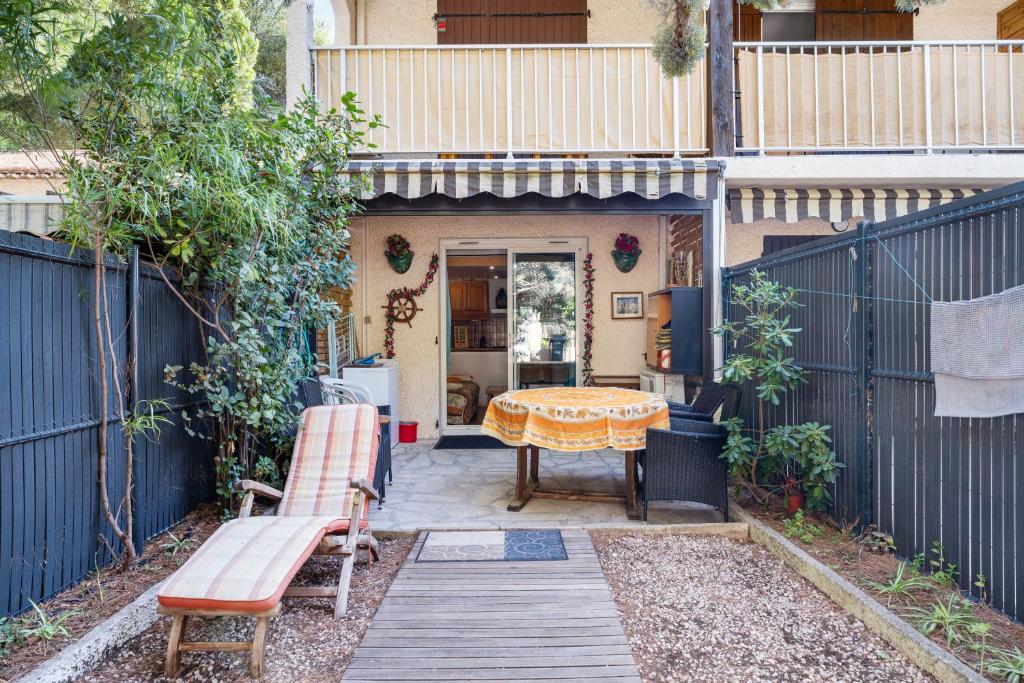 une terrasse avec une table et un banc devant une maison dans l'établissement Beau Studio St Cyr Sur Mer, à Saint-Cyr-sur-Mer