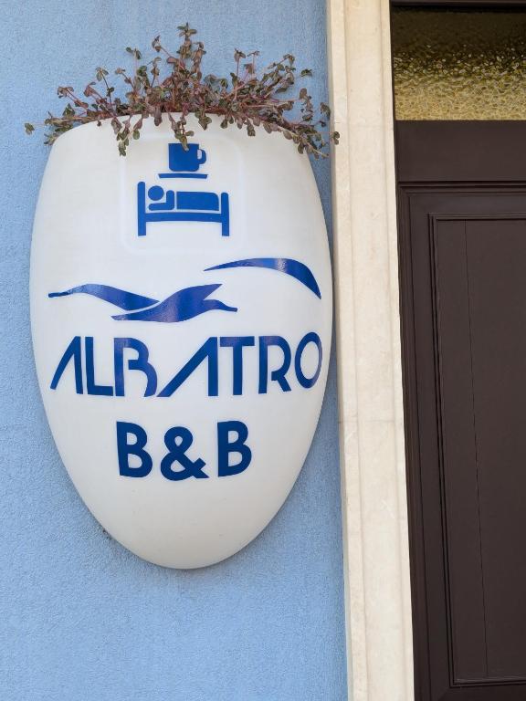 Insegna ovale di Albatro B&B con uccelli marini stilizzati sulla porta d'ingresso in legno