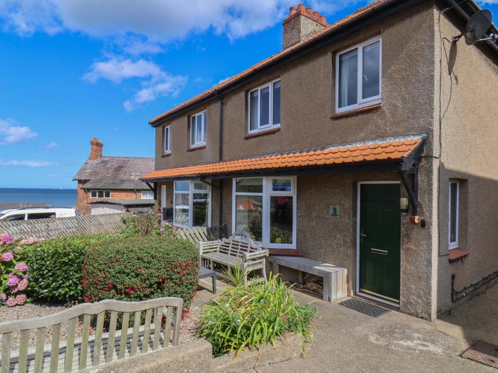 a house with a green door and a bench at Seacliff Cottage in Whitby
