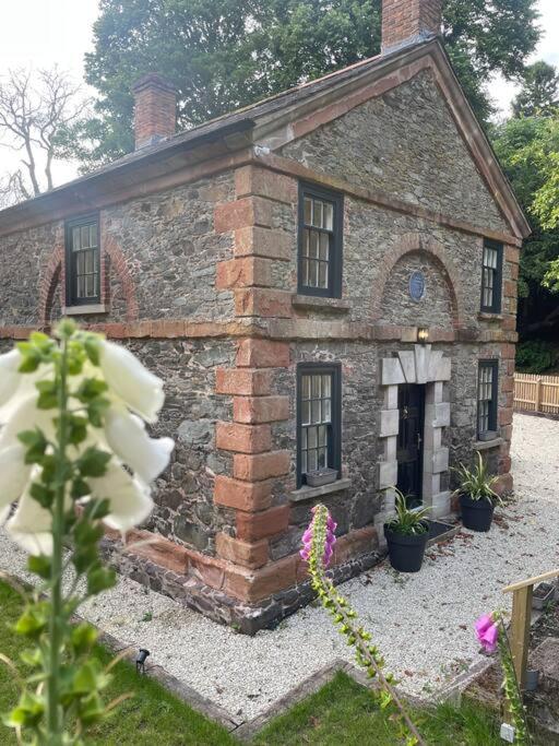 an old brick house with flowers in front of it at Bridge Cottage Upper Malone in Belfast