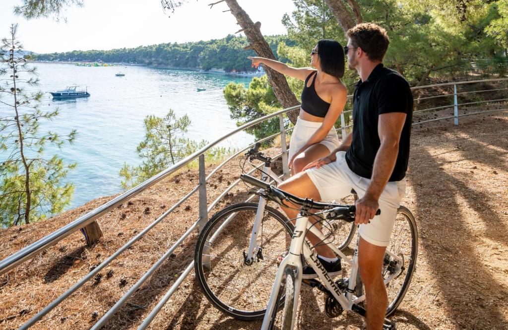 a man and a woman riding a bike by the water at Bluesun Holiday Village Bonaca - Full Board Plus in Bol