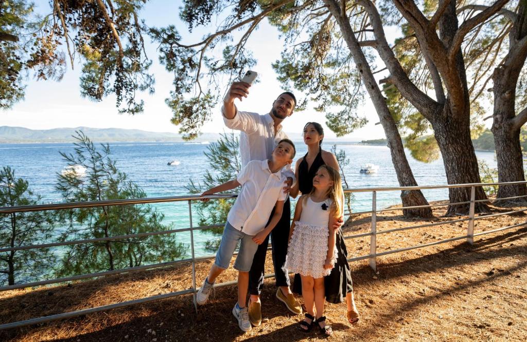 a family posing for a picture by the water at Bluesun Holiday Village Bonaca - Full Board Plus in Bol