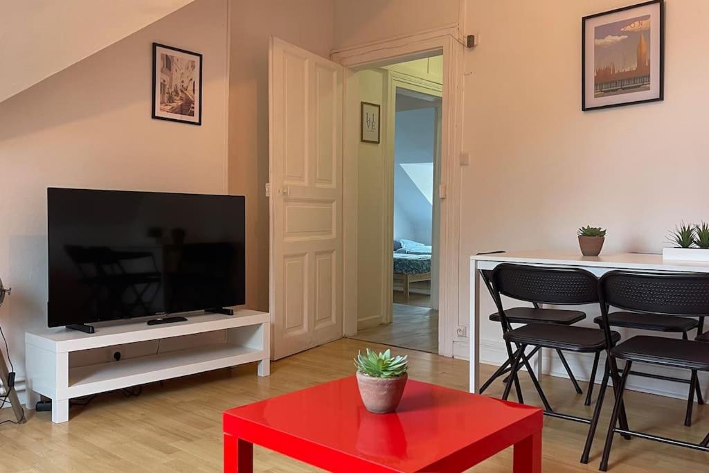 un salon avec une télévision à écran plat et une table rouge dans l'établissement Le Petit Répit - Proche Metz Amnéville Luxembourg, à Serémange-Erzange