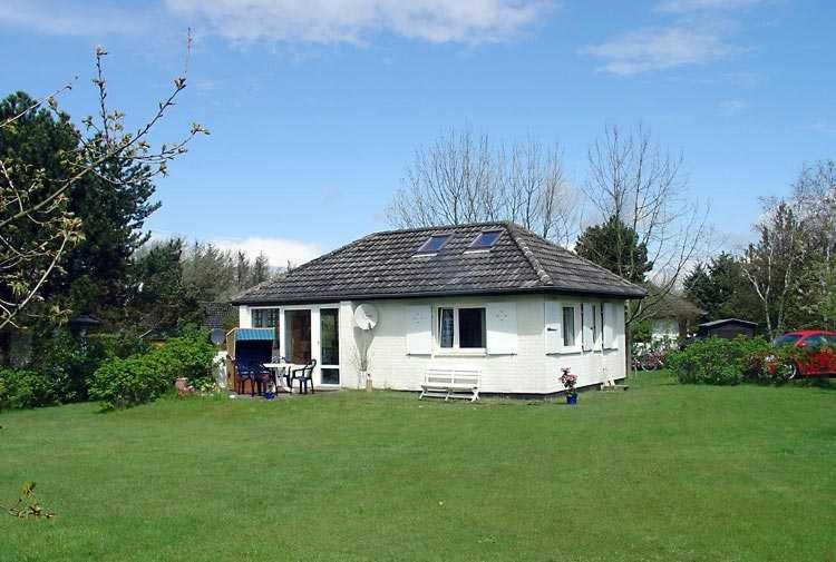 a small white house in a field of grass at Strandhaus mit Kaminofen Bungalow in Goting