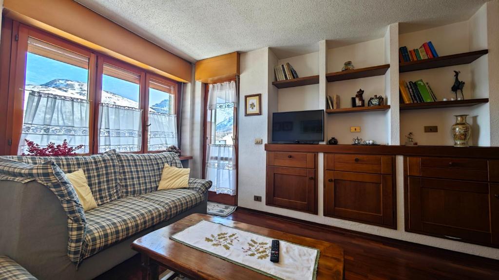 un salon avec un canapé et une télévision dans l'établissement Hostdomus - Violet Apartment, à Sestrières