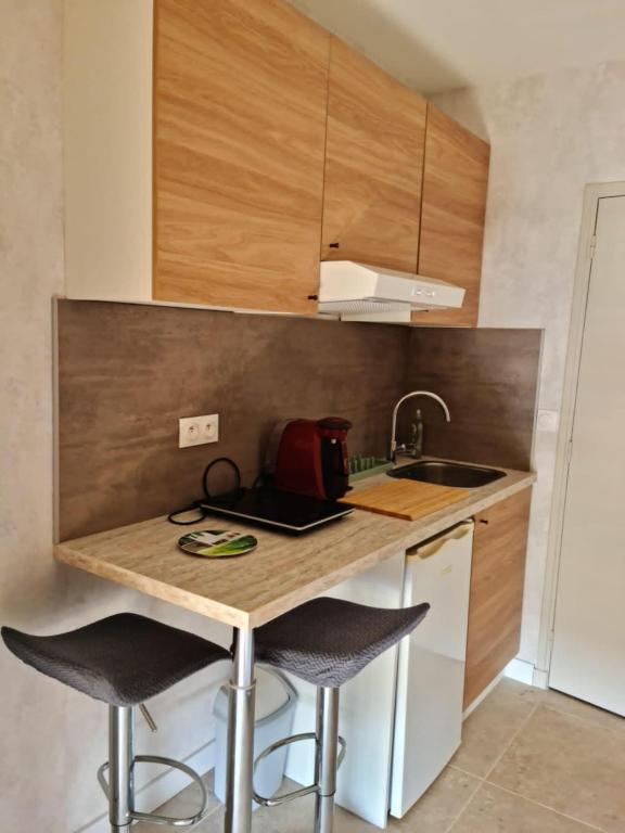 une cuisine avec un comptoir avec des tabourets et un évier dans l'établissement Mini-studio équipé et rénové, à Balaruc-les-Bains