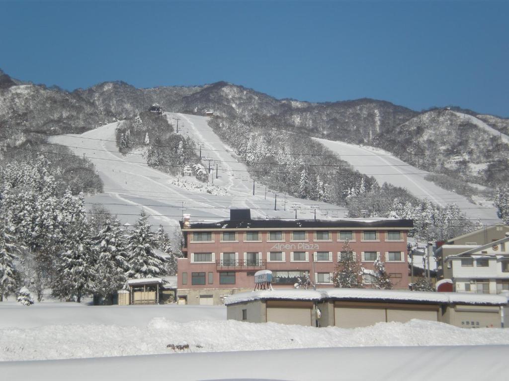 a building on a snowy mountain with a ski slope at Alpen Plaza in Iiyama
