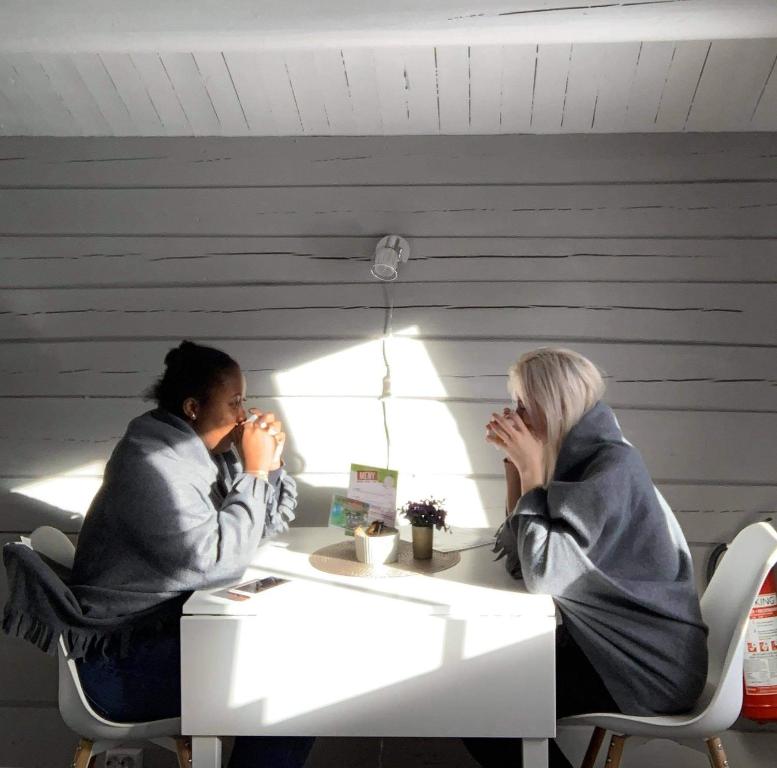 two women sitting at a table with their hands to their faces at Tromsø Lodge & Camping in Tromsø