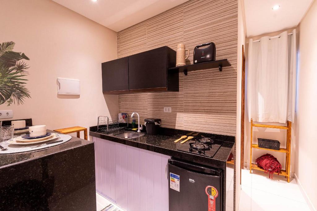 a kitchen with a black counter top and a sink at Ideal p/ 2 Pessoas c/ Cozinha,100M Praia Caminho de Moisés/Maragogi + Estacionamento in Maragogi
