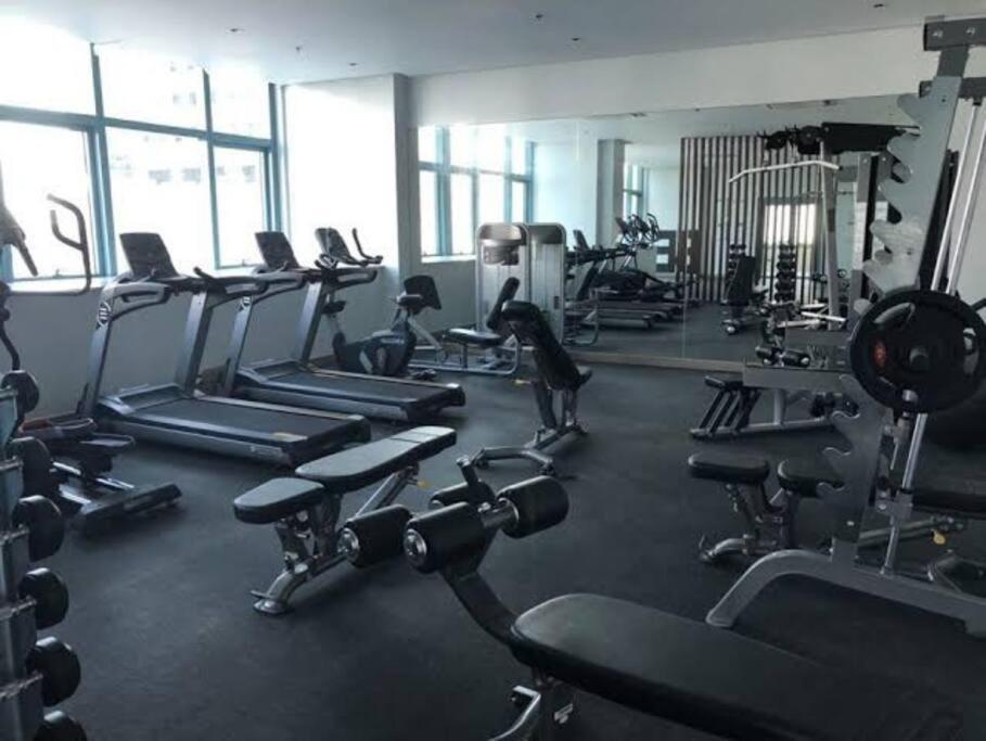 a gym with lots of treadms and cardio machines at BGC 1BR unit linked to Uptown Mall with own parking in Manila