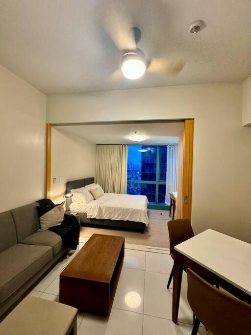 a living room with a bed and a couch at BGC 1BR unit linked to Uptown Mall with own parking in Manila