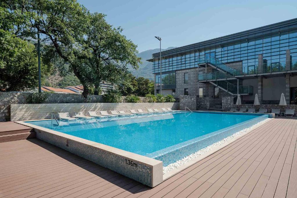 a large swimming pool with chairs and a building at Eurostars Queen of Montenegro in Budva