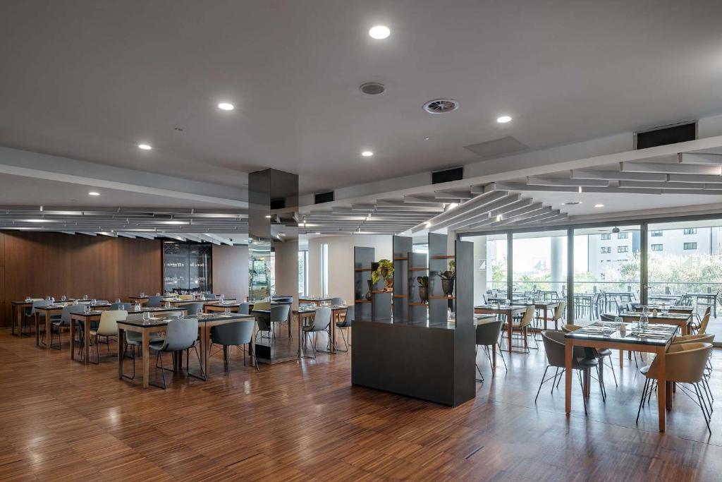 a dining room with tables and chairs and windows at Eurostars Queen of Montenegro in Budva