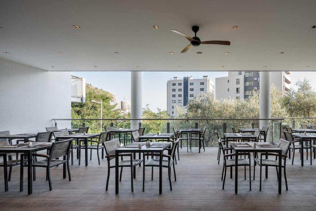 a restaurant with tables and chairs and a ceiling fan at Eurostars Queen of Montenegro in Budva