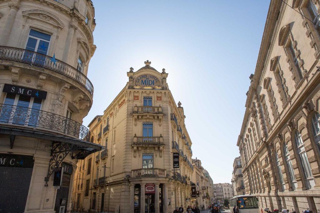 a tall building with a clock on the top of it at Grand Hôtel du Midi Montpellier - Opéra Comédie in Montpellier