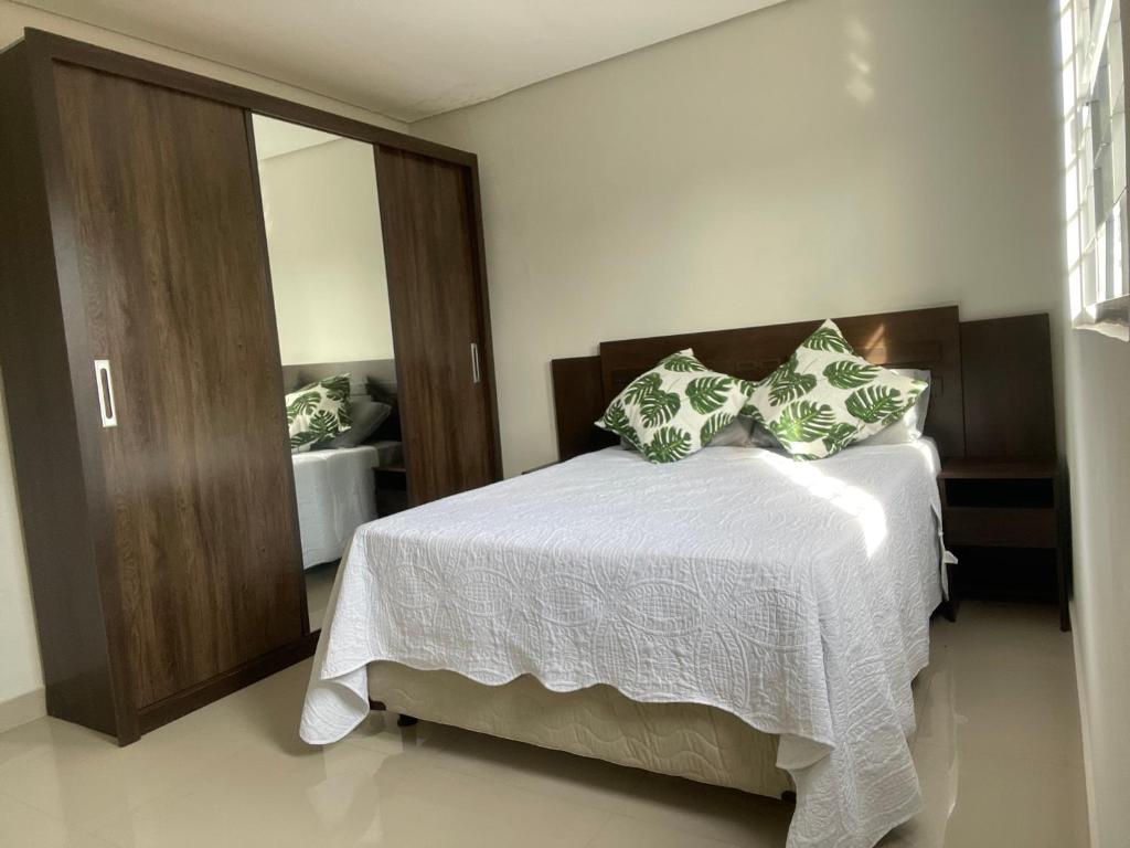 a bedroom with a white bed with pillows on it at Comfort and Style Master Ebony I in Cuiabá