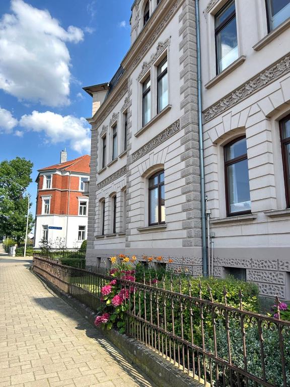 a building with a fence and flowers in front of it at FeWo Lessingstube nahe Jägermeister in Wolfenbüttel