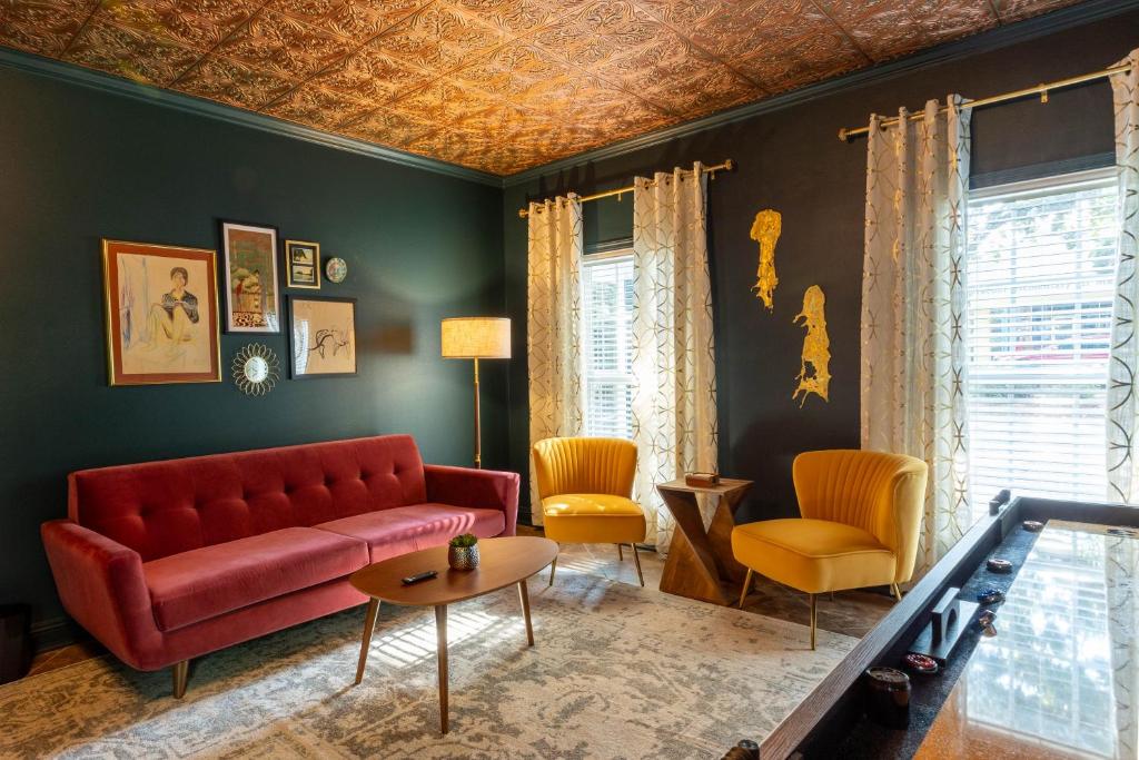 a living room with a red couch and yellow chairs at Downtown Os Artistic Stay W Fire Pit, Game Room! in Ocean Springs