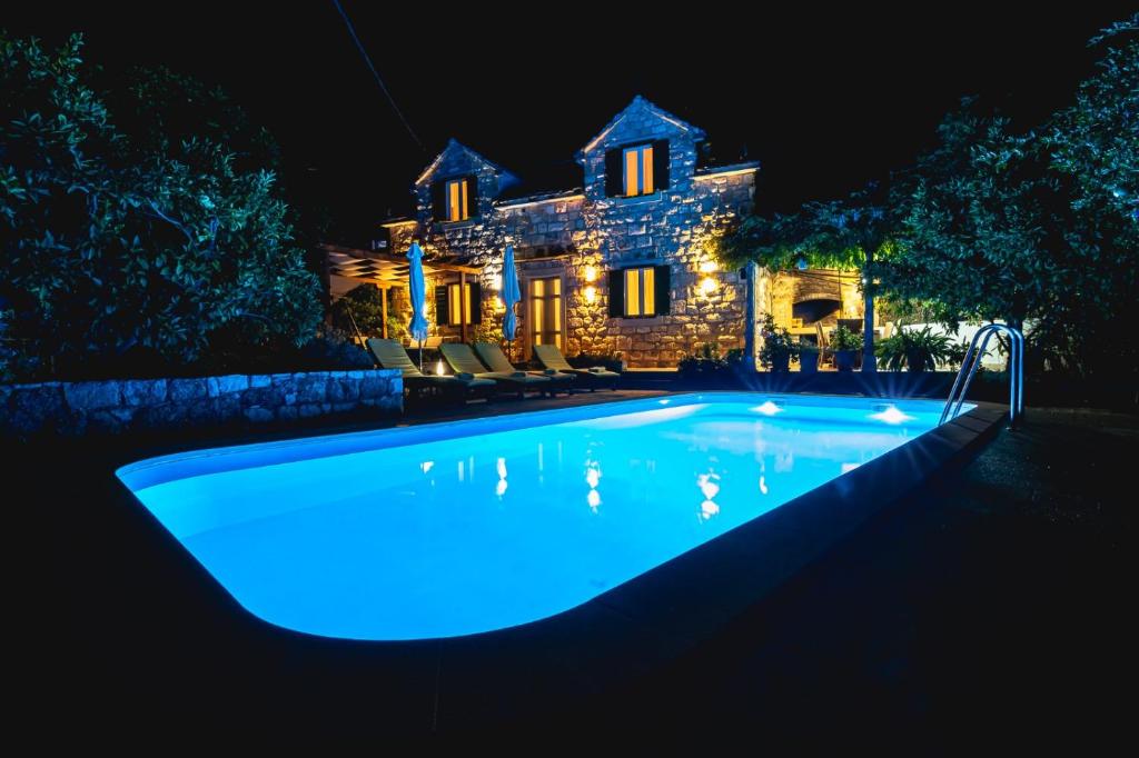 a swimming pool in front of a house at night at Villa matulic in Postira